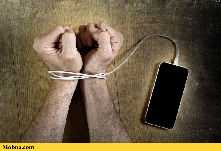 man hands trapped and wrapped on wrists with mobile phone cable as handcuffs in smart phone networking and communication technology addiction concept